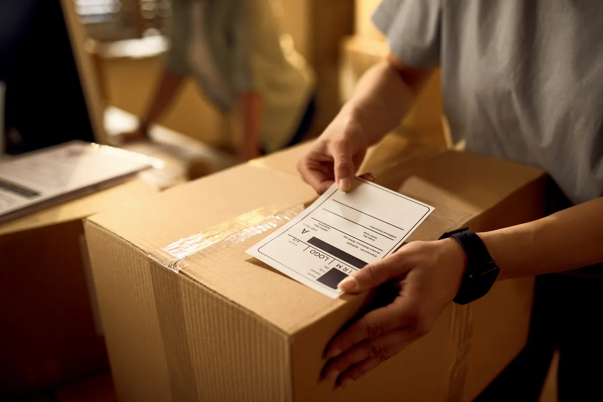 Manos colocando la etiqueta de envío sobre una caja